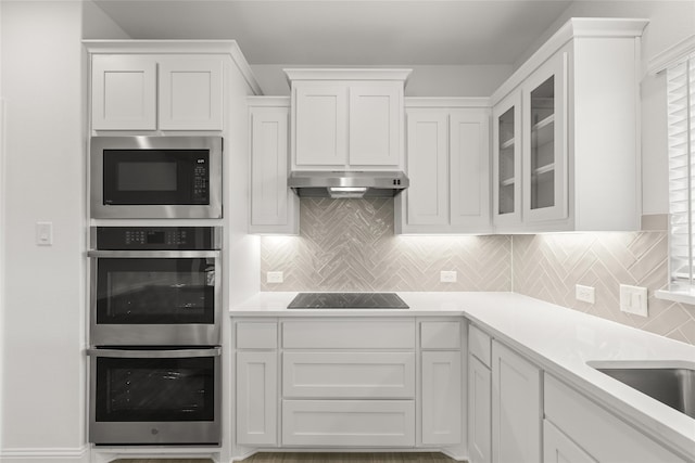 kitchen with tasteful backsplash, white cabinetry, sink, and black appliances