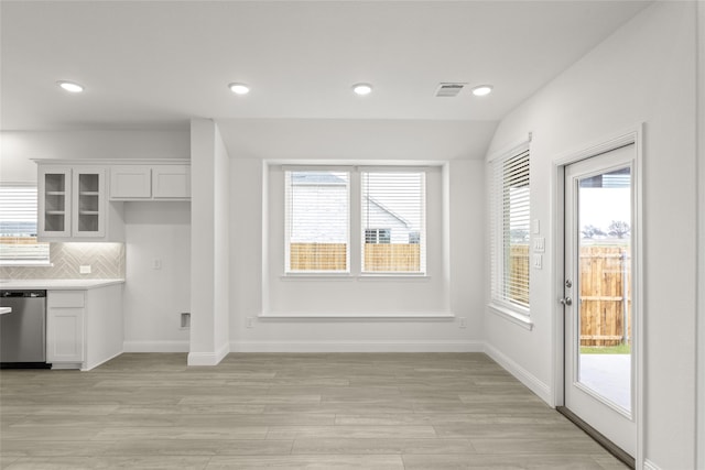 kitchen featuring white cabinetry, dishwasher, light hardwood / wood-style floors, and backsplash