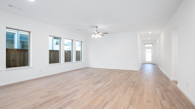 empty room with ceiling fan, a healthy amount of sunlight, and light hardwood / wood-style flooring