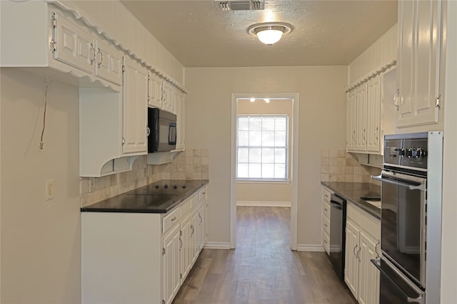 kitchen with hardwood / wood-style flooring, white cabinets, tasteful backsplash, and black appliances