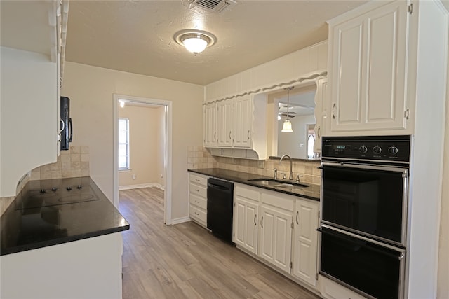 kitchen with white cabinets, black appliances, tasteful backsplash, sink, and light hardwood / wood-style flooring