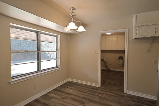 unfurnished dining area featuring dark wood-type flooring and a notable chandelier