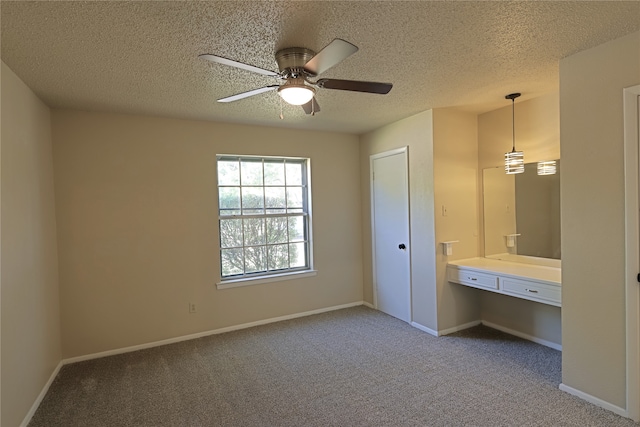 unfurnished bedroom featuring ceiling fan, carpet, a textured ceiling, and built in desk