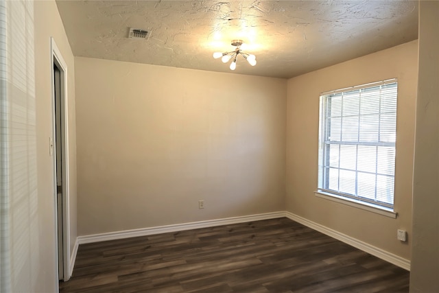 unfurnished room with a textured ceiling, dark hardwood / wood-style flooring, and a chandelier