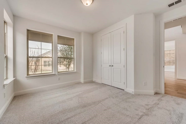 unfurnished bedroom featuring light carpet and a closet