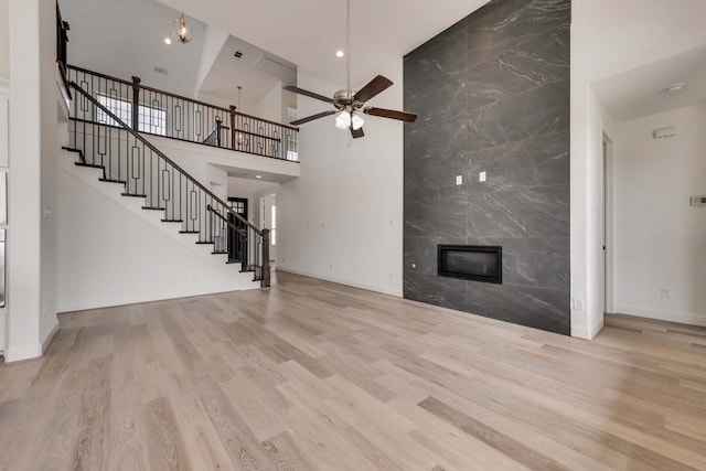 unfurnished living room featuring ceiling fan, stairway, a fireplace, and wood finished floors