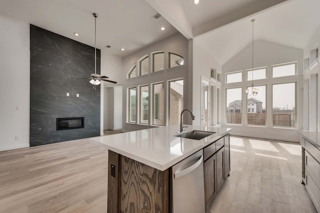 kitchen featuring dishwasher, light hardwood / wood-style floors, sink, hanging light fixtures, and a center island with sink