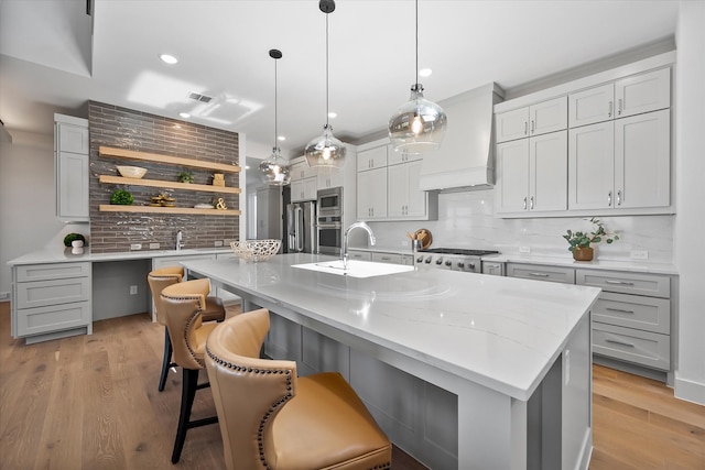 kitchen with stainless steel appliances, light wood finished floors, open shelves, and custom range hood