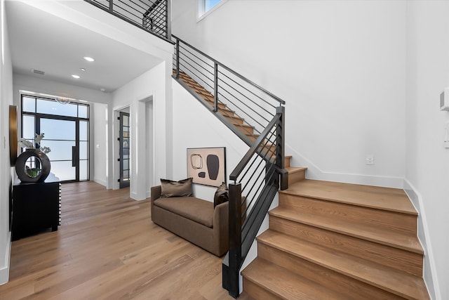 stairs with plenty of natural light, baseboards, and wood finished floors