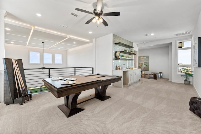 game room featuring light colored carpet, a healthy amount of sunlight, visible vents, and a bar