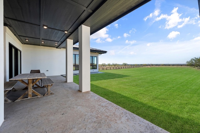 view of yard with a patio area, fence, outdoor dining area, and a rural view