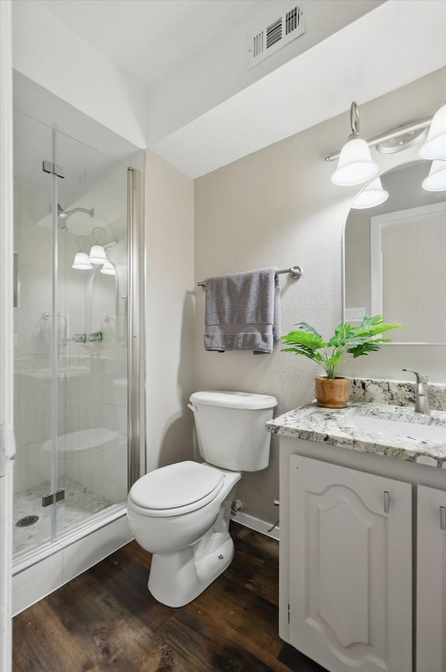 full bathroom featuring toilet, wood finished floors, vanity, visible vents, and a shower stall