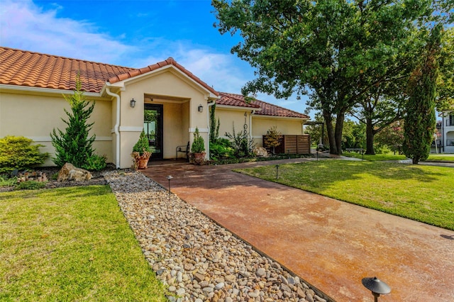 mediterranean / spanish home featuring a tiled roof, a front lawn, and stucco siding