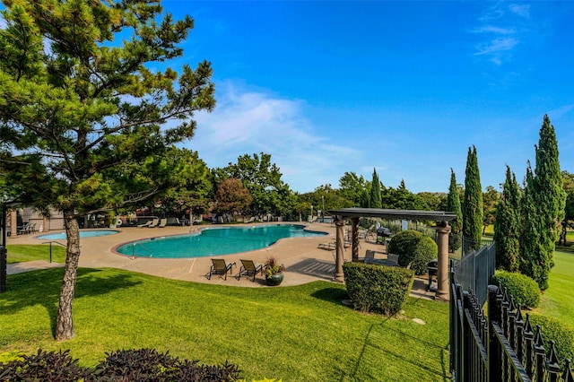 community pool with a patio, a lawn, and fence