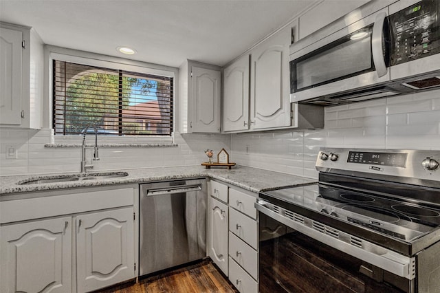 kitchen featuring appliances with stainless steel finishes, dark hardwood / wood-style flooring, tasteful backsplash, sink, and light stone counters