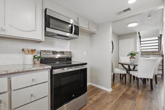 kitchen featuring dark wood-style flooring, visible vents, white cabinets, appliances with stainless steel finishes, and decorative backsplash