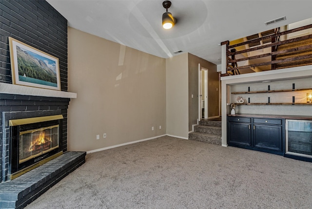 unfurnished living room with ceiling fan, light colored carpet, and a brick fireplace