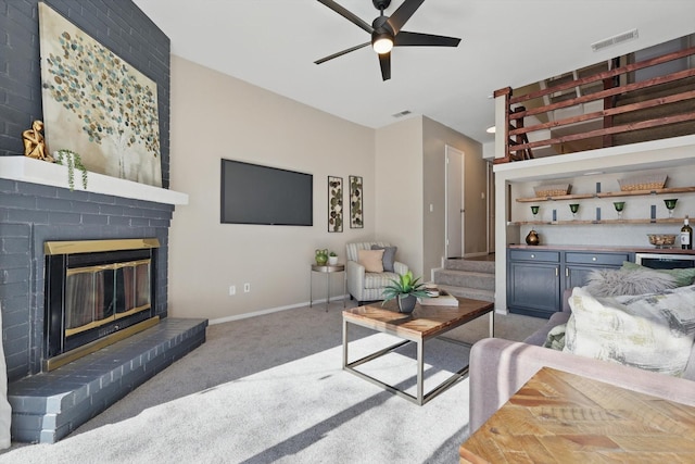 living area with ceiling fan, light colored carpet, a fireplace, visible vents, and stairway