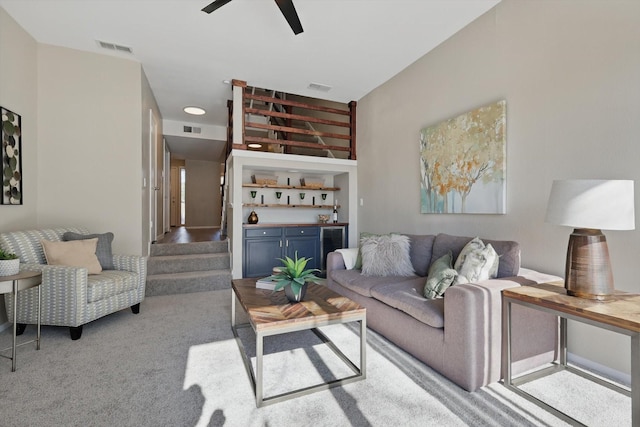 living room featuring light colored carpet, wine cooler, visible vents, and stairway