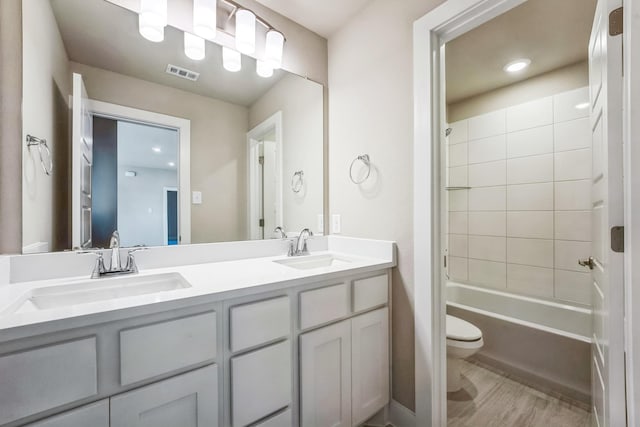 full bathroom featuring tiled shower / bath, hardwood / wood-style flooring, vanity, and toilet