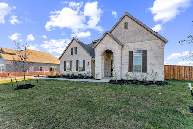 french country home featuring fence and a front lawn