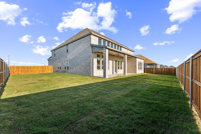 rear view of house with ceiling fan, a patio area, and a yard