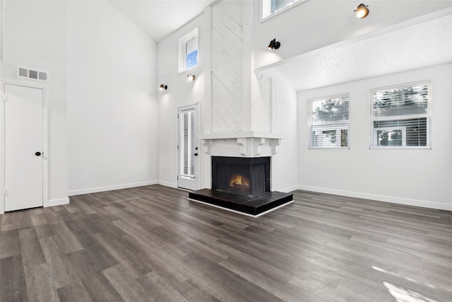 unfurnished living room featuring a large fireplace, high vaulted ceiling, dark hardwood / wood-style flooring, and a textured ceiling