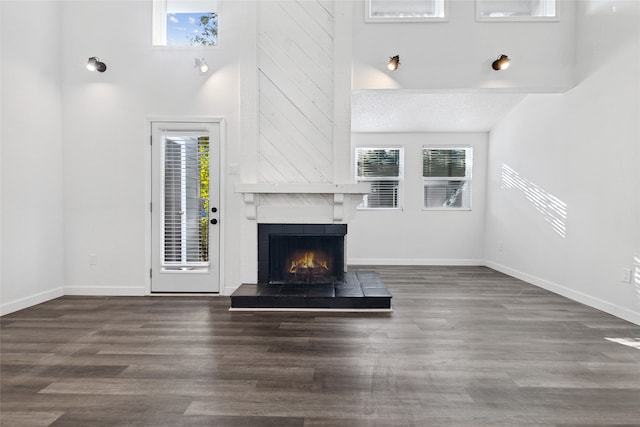 unfurnished living room featuring dark wood-type flooring, a large fireplace, a textured ceiling, and a healthy amount of sunlight