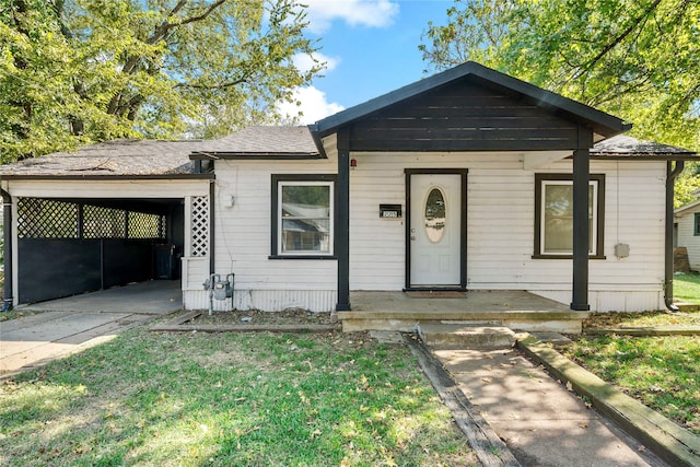 bungalow-style home featuring a front lawn, a porch, and a carport