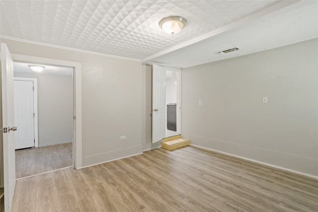 empty room with light hardwood / wood-style flooring and ornamental molding