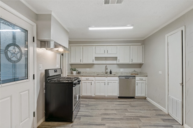 kitchen featuring white cabinets, ornamental molding, sink, appliances with stainless steel finishes, and light wood-type flooring