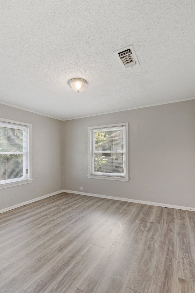 spare room featuring a textured ceiling and light hardwood / wood-style flooring