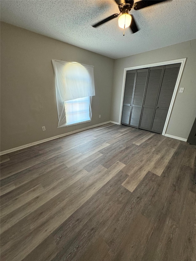 unfurnished bedroom with dark wood-type flooring, a closet, a textured ceiling, and ceiling fan