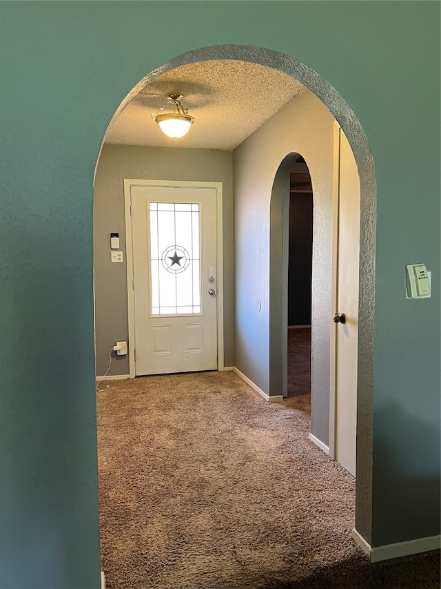 doorway to outside with carpet and a textured ceiling