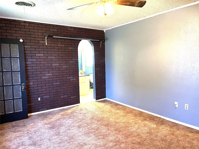 carpeted spare room featuring brick wall, a textured ceiling, crown molding, and ceiling fan