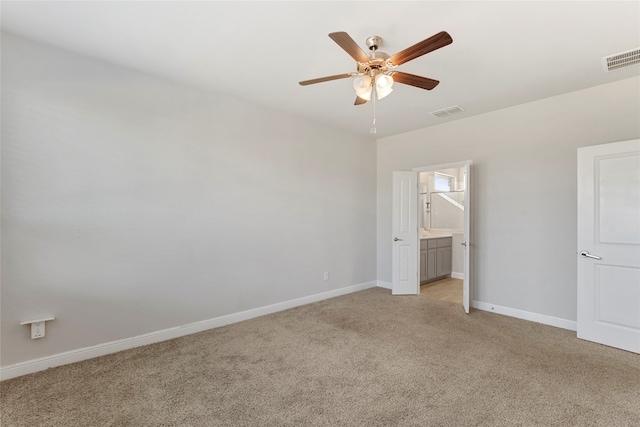 unfurnished bedroom featuring light carpet, ensuite bathroom, and ceiling fan