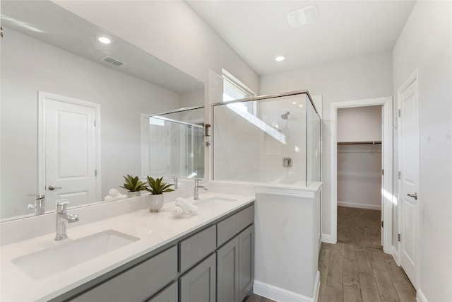 bathroom with hardwood / wood-style floors, vanity, and a shower with door