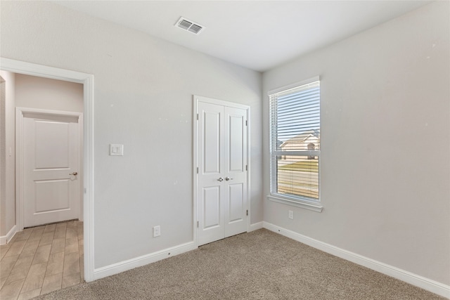 unfurnished bedroom with light wood-type flooring and a closet