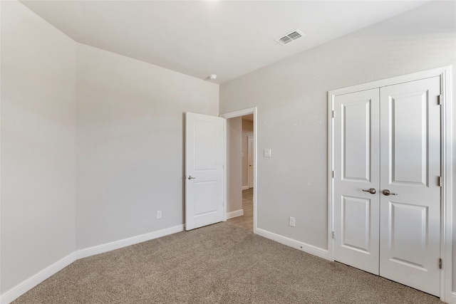 unfurnished bedroom featuring light carpet and a closet