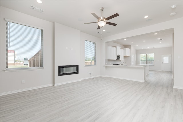 unfurnished living room featuring heating unit, light wood-type flooring, and ceiling fan