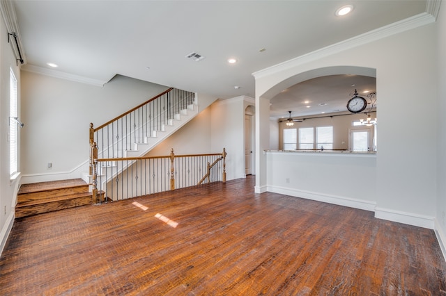 unfurnished living room with ceiling fan with notable chandelier, crown molding, and hardwood / wood-style floors