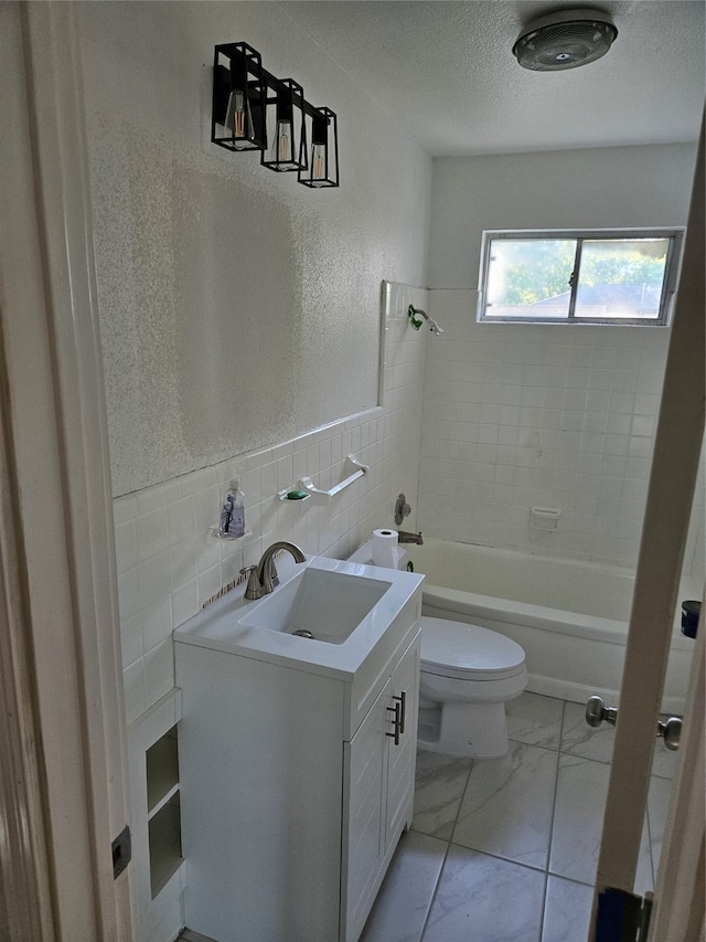 full bathroom with vanity, toilet, tile walls, and tiled shower / bath combo