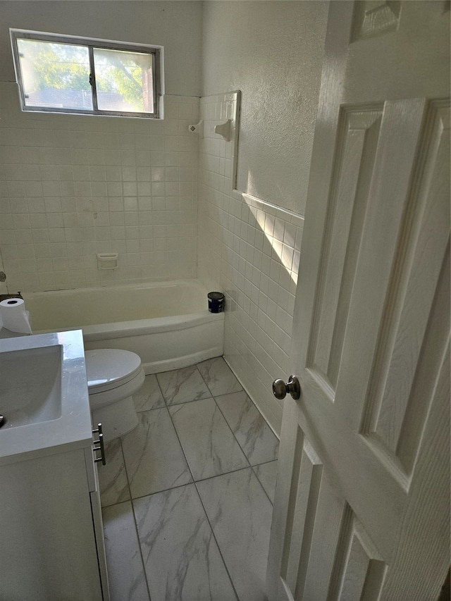 full bathroom with vanity, toilet, tile walls, and tiled shower / bath combo