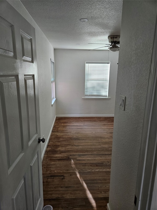 empty room featuring a textured ceiling, ceiling fan, and dark hardwood / wood-style floors