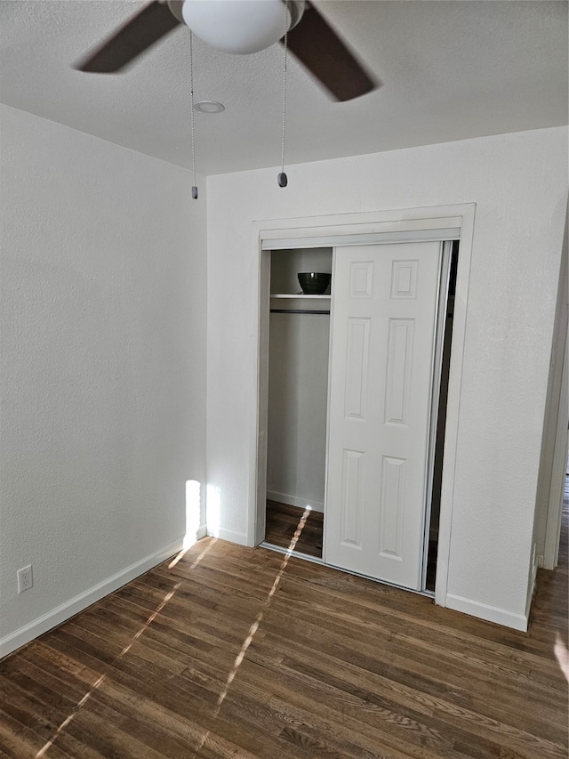 unfurnished bedroom with a textured ceiling, a closet, ceiling fan, and dark wood-type flooring