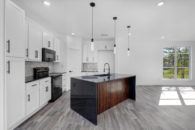 kitchen with black appliances, sink, light wood-type flooring, an island with sink, and white cabinets