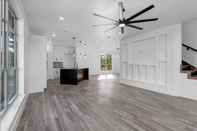 unfurnished living room with ceiling fan, sink, and hardwood / wood-style floors