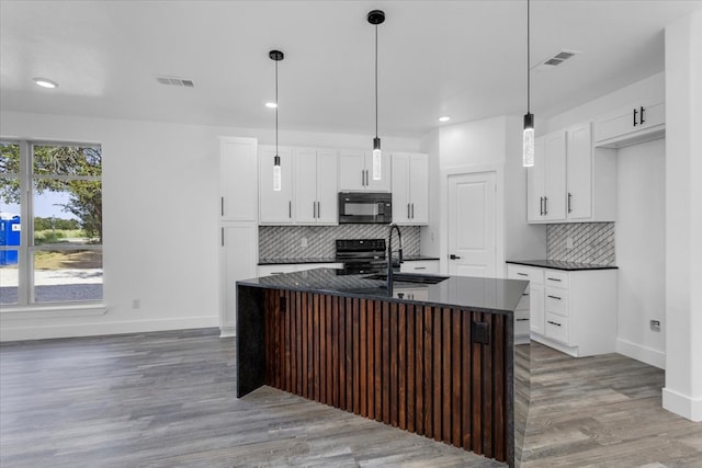 kitchen with white cabinetry, pendant lighting, and a kitchen island with sink