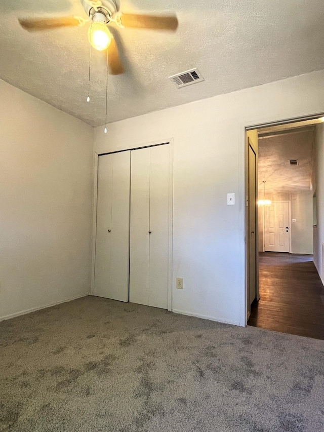 unfurnished bedroom with a closet, a textured ceiling, dark hardwood / wood-style floors, and ceiling fan