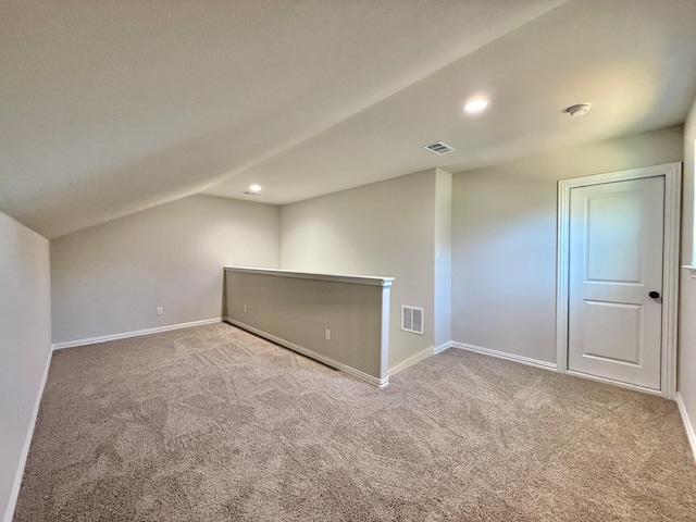 unfurnished room with light colored carpet and lofted ceiling